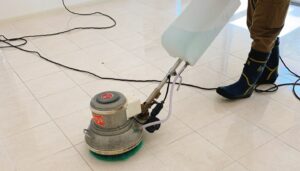 マンションの共用部の床を、作業員がポリッシャーで清掃している様子