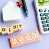 「年金戦略」と書かれた札と「POINT」の木製ブロック、電卓と家の模型