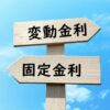 「変動金利」と「固定金利」と書かれ、左右反対を指す木の道しるべと青空